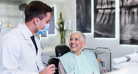 Dentist with clipboard talking to smiling patient