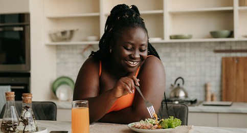 Woman smiling while eating in kitchen