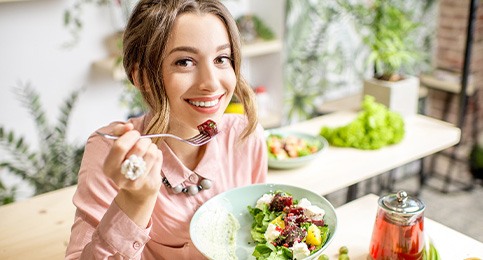 Woman smiling while eating healthy meal in kitchen