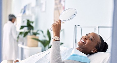 Woman smiling at reflection in handheld mirror