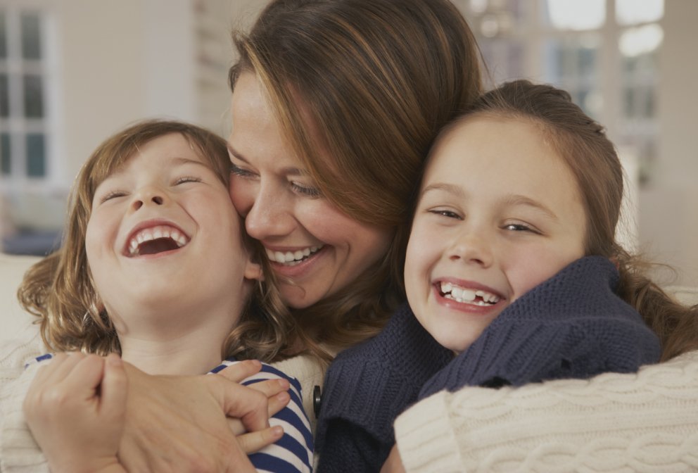 Mother and two children with healthy smiles after dental services