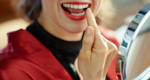 patient in reno smiling in the mirror after teeth whitening