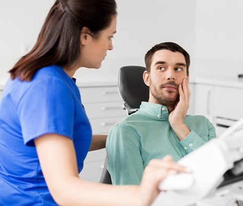 Man holding cheek during emergency dentistry visit