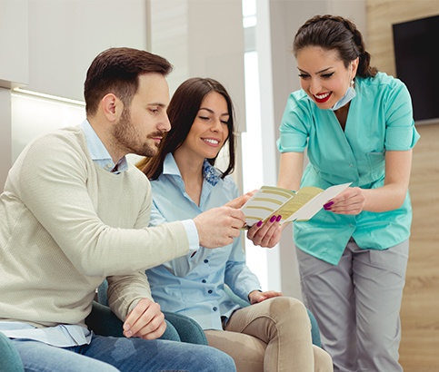 Dental team member giving patients dental insurance paperwork