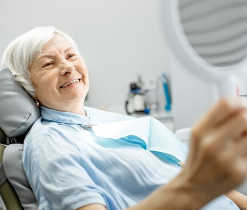 Woman in dental chair looking at smile in mirror
