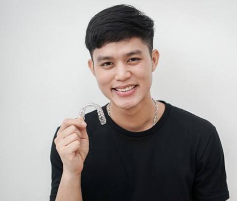 young man holding an Invisalign aligner 