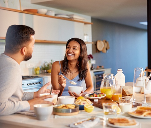 Couple smiling at each other while eating in kitchen