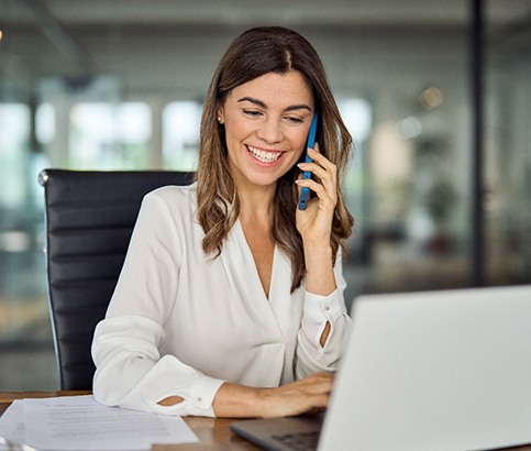 Woman smiling while talking on phone in office