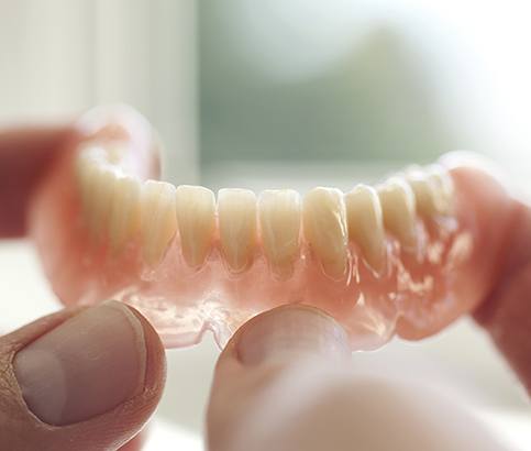 Hand holding a full denture