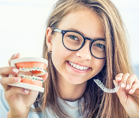Young woman holding a model smile and Invisalign tray