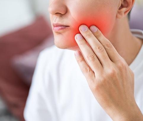 a person touching their jaw due to failed dental implant