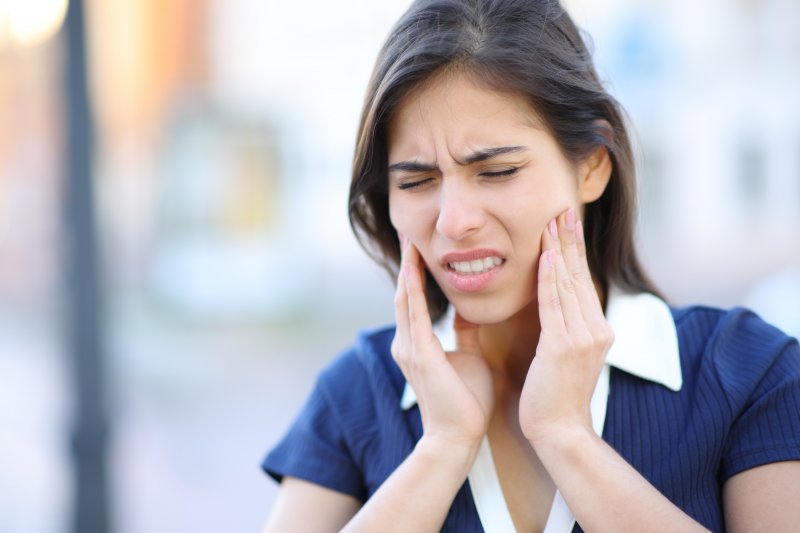 Woman holds mouth in pain