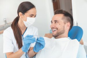 Dentist and patient smiling while dentist holds clear aligner. 