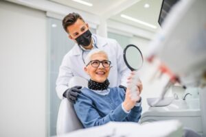 Older lady looking into mirror in dentist's chair.